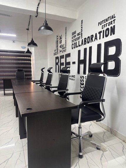 Co-office desks and chairs beside the Ree-Hub feature wall